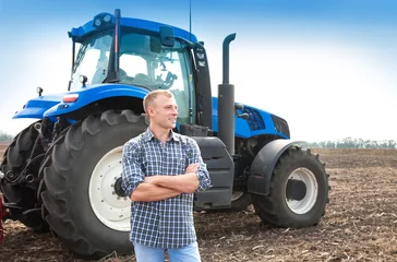 Cercles muraux Tracteur Young attractive man near a tractor. Concept of agriculture.