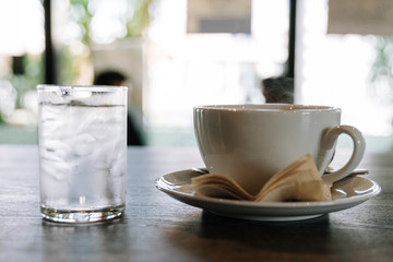Cup of hot coffee and ice water put on the wooden table in coffee shop