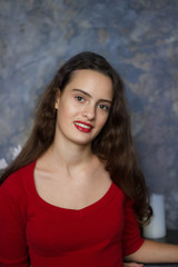 Smyling young girl in a red dress on a dark background