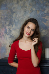 Fototapeta premium Smyling young girl in a red dress on a dark background