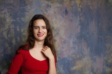 Naklejka premium Smyling young girl in a red dress on a dark background