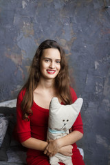 Fototapeta premium Smyling young girl in a red dress holding lovely toy