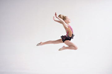 Fototapeta na wymiar Little girl gymnast, performs various gymnastic and fitness exercises.