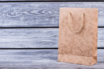 Brown shopping bag with copy space. Paper gift bag with plain design on vintage wooden background.