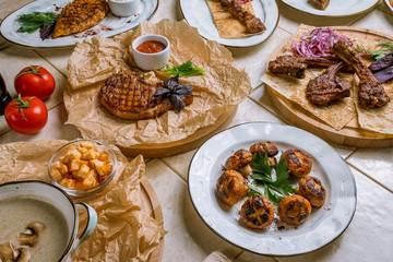 Assorted dishes top view pork ribs, beef steak, rack of lamb, dorado, cream soup, salmon kebab