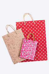 Colorful paper bags for shopping. Three different gift bags with printing. Holiday shopping concept.