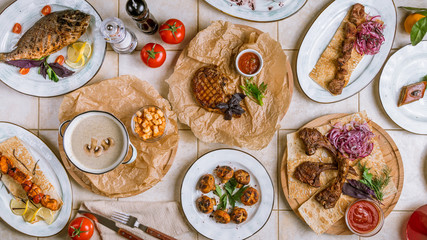 Assorted dishes top view pork ribs, beef steak, rack of lamb, dorado, cream soup, salmon kebab