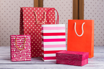 Fototapeta na wymiar Group of colorful shopping bags. Set of different gift packets with handles and pink gift box. Holiday purchasing concept.