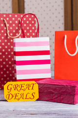 Fototapeta premium Colorful shopping bags with printing. Paper gift bags with handles. Gift box and yellow card with inscription great deals. Shopaholic holidays concept.