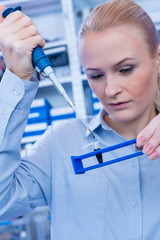 Female technician in laboratory of genetics - reprogenetics. Young technician use dispenser for...