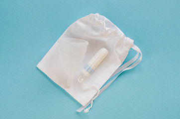 Menstrual cup and tampon on a blue background.