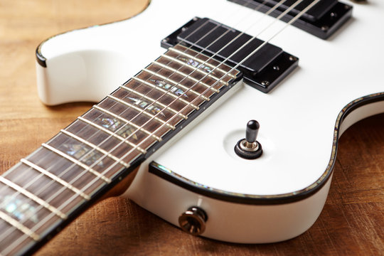 Body and fretboard of modern electric guitar on rustic wooden background. 