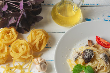 Pasta Fetuccine with creamy alfredo mushroom sauce and cheese on a white plate. Garlic, olive oil and champignons. Selective focus. Old wooden backgraund.