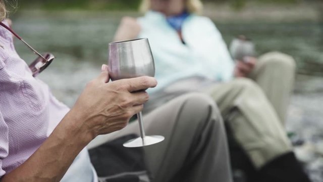 Selective focus shot of two woman drinking from metal wineglass outdoors in the nature. Blurred background.