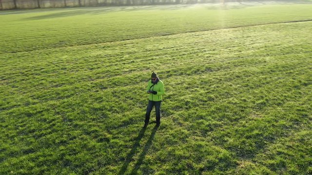 aerial drone shot circling in an elypse way around man standing in the field