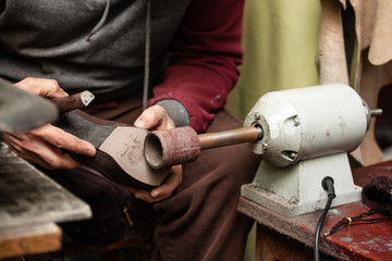 close-up of male shoemaker hands sanding a sole on a machine tool