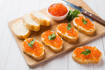 Sandwiches with red salmon caviar on a wooden Board. White table top.