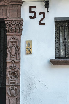 White wall of house exterior with hand painted number 52 on stucco surface, Mexico city