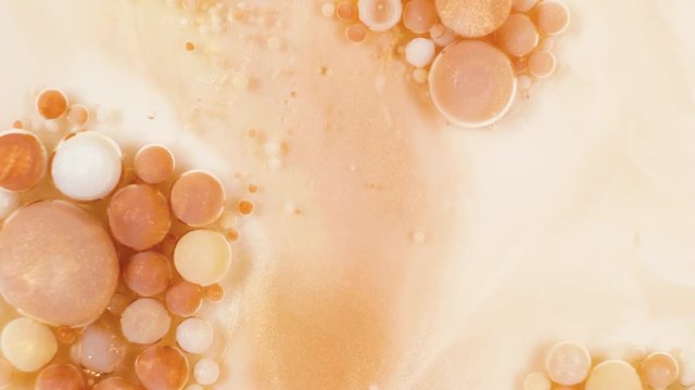 Colorful paint in golden bubbles organically moves in the sand liquid