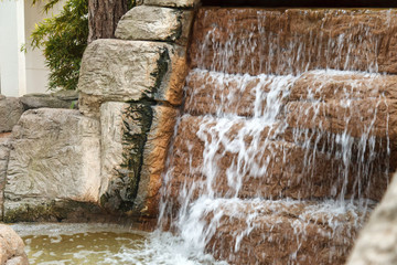 Clear water flows through an artificial waterfall cascade