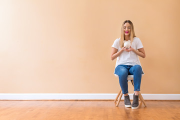Fototapeta premium Young woman with a piggy bank in a chair