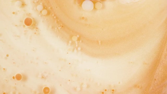 Colorful paint in golden bubbles organically moves in the sand liquid