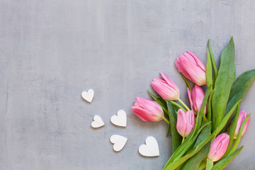Bouquet  of pink tulips and wooden hearts pattern. Concept for Valentine's Day, womens day and other romantic events. Top view, close-up, flat lay on white wooden background