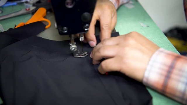 Close up seamstress using sewing machine stiching fabric together to create clothing.