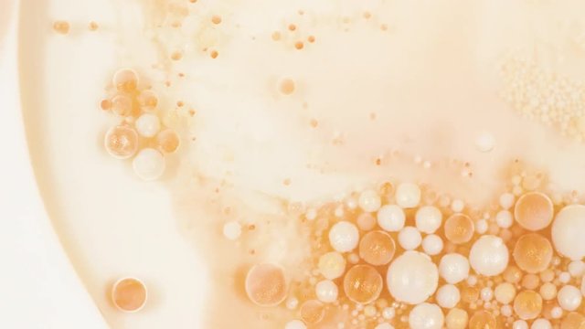 Colorful paint in golden bubbles organically moves in the sand liquid