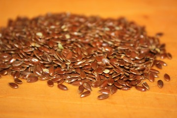 Brown Flax Seeds in a Wooden Spoon with a wooden background spilling over the edge with copy space Close Up macro detail