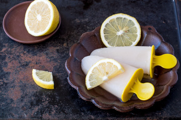 Lemon flavored homemade ice cream on a round ceramic small plate on a dark background. 