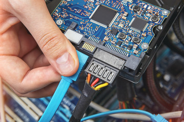 Connecting SATA cable to motherboard of personal computer.