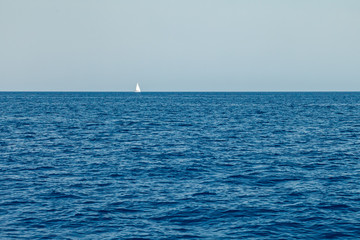 Obraz premium A lone white sailing yacht sails in the waters of the Mediterranean