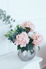 Pink hydrangeas in a transparent vase on a white table