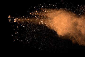 abstract brown powder splatted background. Colorful powder explosion on black background. Colored...