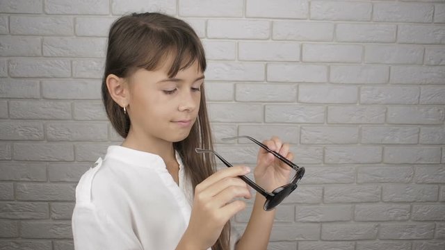 Perforated glasses. Exercise for the eyes. Little girl puts on pinhole glasses.
