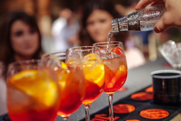 Bartender pours water into a glass with a cocktail. Barman making a cocktail. Close-up