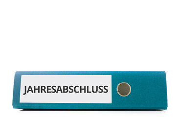 blauer liegender Aktenordner mit Beschriftung Jahresabschluss vor hellem Hintergrund