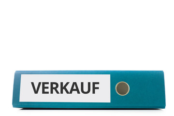 blauer liegender Aktenordner mit Beschriftung Verkauf vor hellem Hintergrund