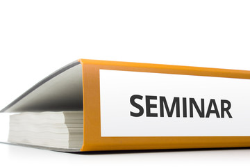 oranger Aktenordner gefüllt mit Papierseiten und Beschriftung Seminar liegend vor weißem...