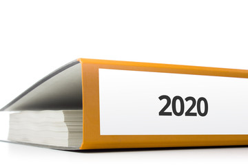 oranger Aktenordner gefüllt mit Papierseiten und Beschriftung 2020 liegend vor weißem Hintergrund
