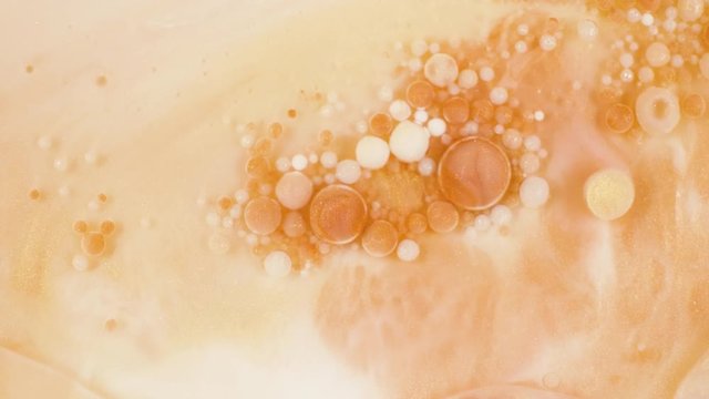Colorful paint in golden bubbles organically moves in the sand liquid
