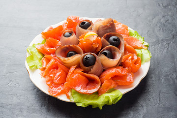 Gourmet restaurant serving a plate of smoked salt, raw white fish fillets and salmon. Delicacy fresh seafood dish with catfish, salmon meat with olives on a plate close-up