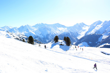 Fototapeta na wymiar People enjoying skiing on prepared slopes in the Alps on sunny day. Beautiful snowy trees in the mountains. Perfect winter holidays destination for family in modern comfortable Alpine ski resort. 