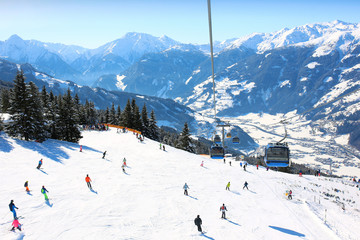 People enjoying skiing on prepared slopes in the Alps on sunny day. Modern comfortable gondola lift...