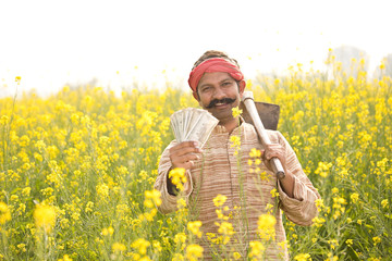Farmer holding Indian Rupee notes in field
