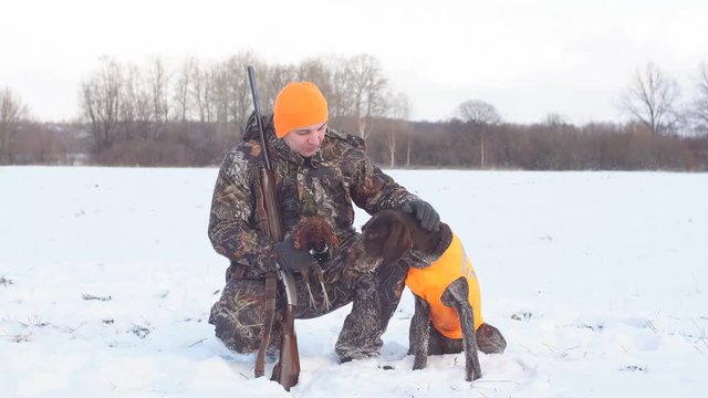 pleasant man is thanking his dog for help during hunting. rest, excellent weather for hunting