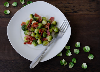Brussels sprouts with ham on dark background. Top view.