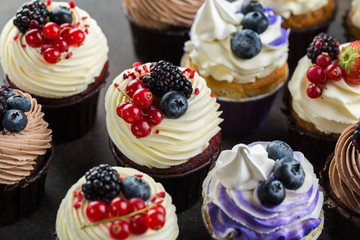 Various sweet cupcakes on brown stone background. 
