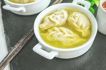Asian dumplings in broth in a white bowl. Selective focus